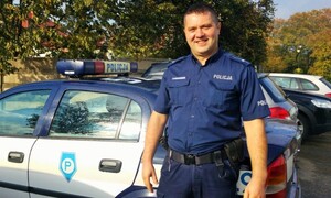 Policjant stoi przy radiowozie.