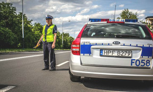 policjant stojący przy radiowozie i zatrzymujący pojazdy do kontroli