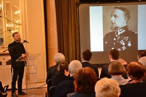 Pierwszy z prelegentów konferencji podczas omawiania patronów 100-letniej formacji jaka jest Policja Państwowa. na ekranie zdjęcie jednego z byłych KGP.