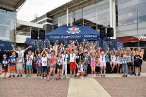 pamiątkowe zdjęcie dzieci na tle baneru 100 lat policji