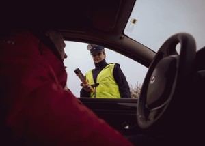 policjantka z alcoblow stojąca przy kontrolowanym pojeździe, za którego kierownicą siedzi mężczyzna