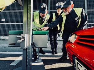 Czerwony samochód, policjanci i inspektorzy transportu drogowego sprawdzają światła.