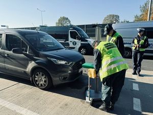 Ciemny samochód, policjanci i inspektorzy transportu drogowego sprawdzają światła.