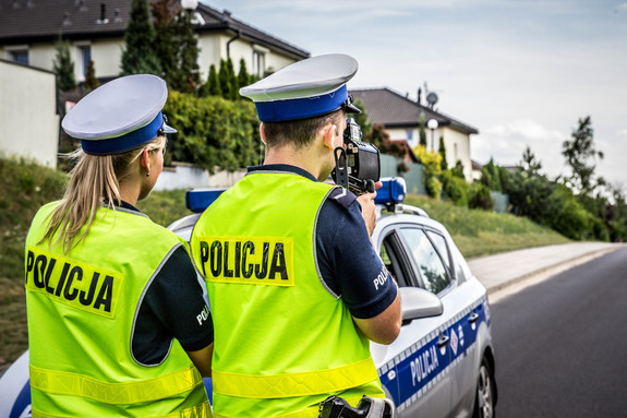 Policjanci z ruchu drogowego stoją przy radiowozie,