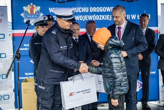 Policjanci wręczają nagrody wygranym dzieciom.