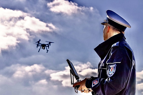 Policjant steruje dronem.