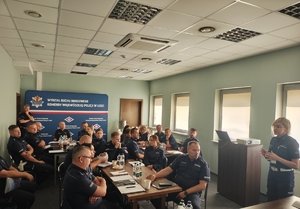 Sala, policjanci siedzą przy stole.