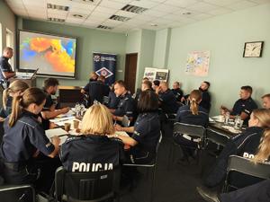 Sala, policjanci siedzą przy stole.