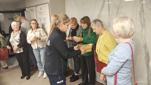 Policjantka rozdaje odblaski seniorom.