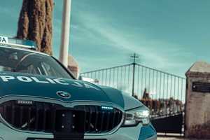 radiowóz na tle bramy cmentarnej.