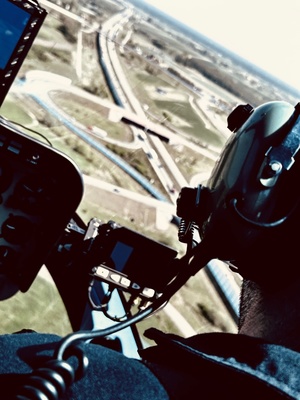 widok z środka helikoptera, na pierwszym planie widać głowę pilota ze słuchawkami.