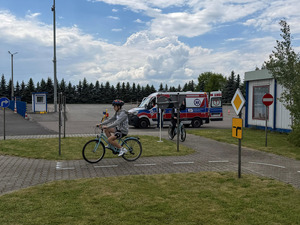 Uczeń na rowerze, w tle karetka.