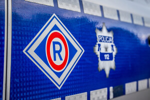 Bok oznakowanego radiowozu Policji.