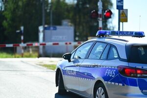 Radiowóz przy zamkniętym przejeździe kolejowym.