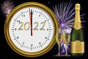 Na pierwszym planie okrągła tarcza zegara, na którym jest data 2022, a  wskazówki zbliżają się do godziny 12. Po prawej stronie ilustracji widnieją kieliszki oraz butelka wypełniona szampanem, w tle rozbłyskujące się kolorowe fajerwerki.