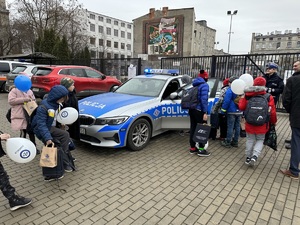 Dzieci oglądają oznakowany radiowóz policji.