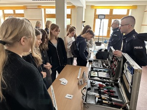 Policjant pokazujący uczniom walizki ze sprzętem do ujawniania śladów.