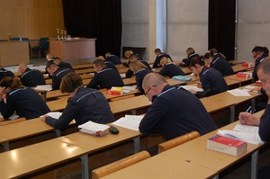 Policjanci w mundurach, rozwiązujący na auli test wiedzy w ramach konkursu.