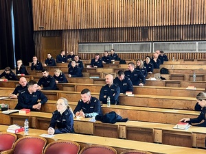 Policjanci w mundurach, rozwiązujący na auli test wiedzy w ramach konkursu.