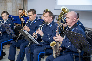 Policjanci w mundurach graja na instrumentach.