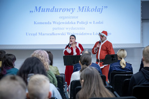 Kobieta i mężczyzna w strojach mikołaja śpiewają.