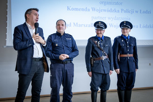 Czterech mężczyzn w tym policjanci w mundurach stoją w rzędzie.