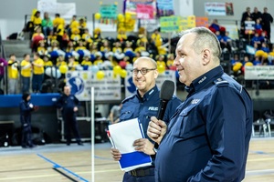 Zmagania dzieci podczas zawodów sportowych na sali gimnastycznej w obecności policjantów i aktorów.