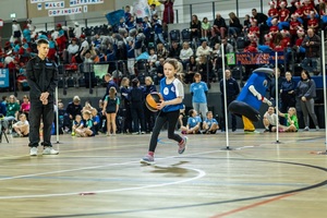 Zmagania dzieci podczas zawodów sportowych na sali gimnastycznej w obecności policjantów i aktorów.