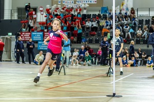 Zmagania dzieci podczas zawodów sportowych na sali gimnastycznej w obecności policjantów i aktorów.