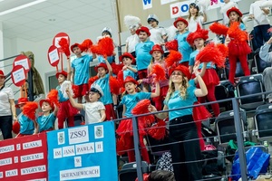 Zmagania sportowe dzieci na sali gimnastycznej w obecności policjantów  i aktorów.