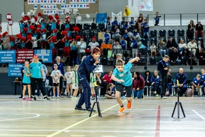 Zmagania sportowe dzieci na sali gimnastycznej w obecności policjantów  i aktorów.