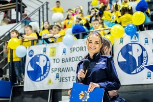 Zmagania sportowe dzieci na sali gimnastycznej w obecności policjantów  i aktorów.