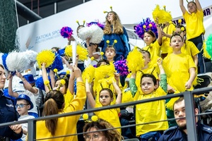 Zmagania sportowe dzieci na sali gimnastycznej w obecności policjantów  i aktorów.