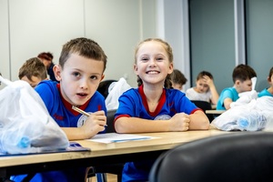 Zmagania sportowe dzieci na sali gimnastycznej w obecności policjantów  i aktorów.