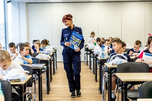 Zmagania sportowe dzieci na sali gimnastycznej w obecności policjantów  i aktorów.