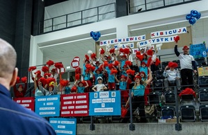 Zmagania sportowe dzieci na sali gimnastycznej w obecności policjantów  i aktorów.