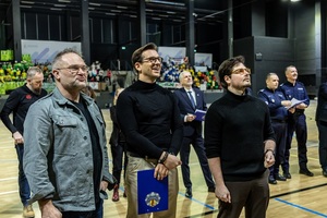 Zmagania sportowe dzieci na sali gimnastycznej w obecności policjantów  i aktorów.