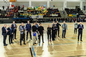 Zmagania dzieci podczas zawodów sportowych na sali gimnastycznej w obecności policjantów i aktorów.