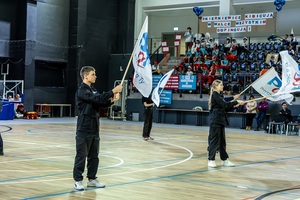 Zmagania dzieci podczas zawodów sportowych na sali gimnastycznej w obecności policjantów i aktorów.