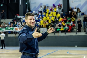 Zmagania dzieci podczas zawodów sportowych na sali gimnastycznej w obecności policjantów i aktorów.