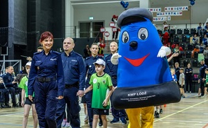 Zmagania dzieci podczas zawodów sportowych na sali gimnastycznej w obecności policjantów i aktorów.