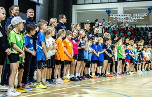 Zmagania dzieci podczas zawodów sportowych na sali gimnastycznej w obecności policjantów i aktorów.