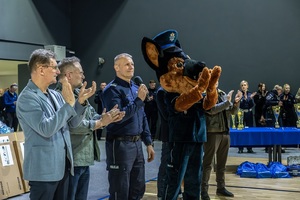 Zmagania dzieci podczas zawodów sportowych na sali gimnastycznej w obecności policjantów i aktorów.