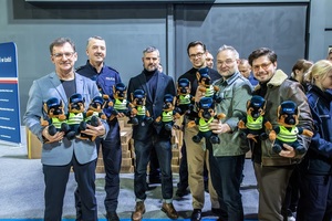 Zmagania dzieci podczas zawodów sportowych na sali gimnastycznej w obecności policjantów i aktorów.