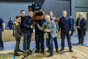 Zmagania dzieci podczas zawodów sportowych na sali gimnastycznej w obecności policjantów i aktorów.