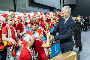 Zmagania dzieci podczas zawodów sportowych na sali gimnastycznej w obecności policjantów i aktorów.
