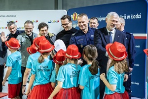 Zmagania dzieci podczas zawodów sportowych na sali gimnastycznej w obecności policjantów i aktorów.