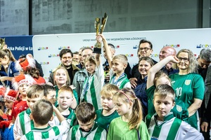 Zmagania dzieci podczas zawodów sportowych na sali gimnastycznej w obecności policjantów i aktorów.