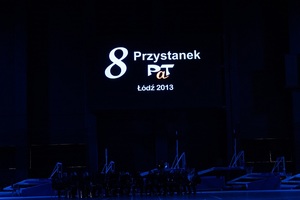 Młodzież w czarnych mundurach ćwiczebnych macha flagami z napisem PaT.