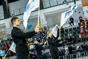 Młodzież w czarnych mundurach ćwiczebnych macha flagami z napisem PaT.